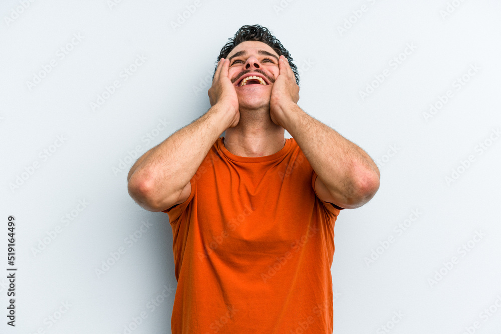 Young caucasian man isolated on blue background laughs joyfully keeping hands on head. Happiness concept. Young caucasian man isolated on blue background laughs joyfully keeping hands on head. Happiness concept.