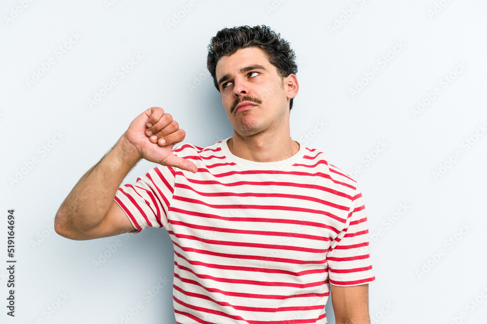 Fototapeta premium Young caucasian man isolated on blue background showing a dislike gesture, thumbs down. Disagreement concept.