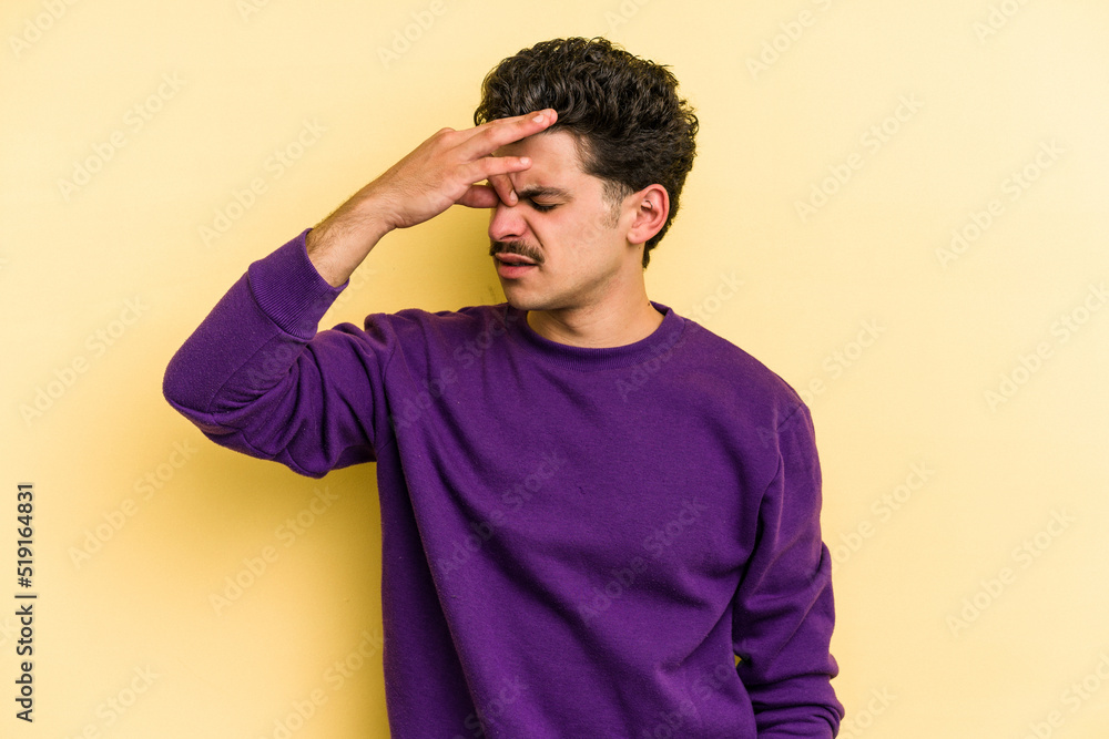 Young caucasian man isolated on yellow background having a head ache, touching front of the face. Young caucasian man isolated on yellow background having a head ache, touching front of the face.