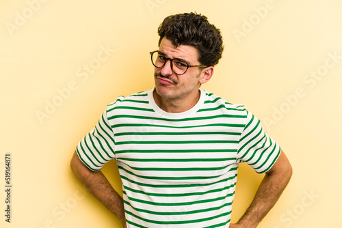 Young caucasian man isolated on yellow background confused  feels doubtful and unsure.