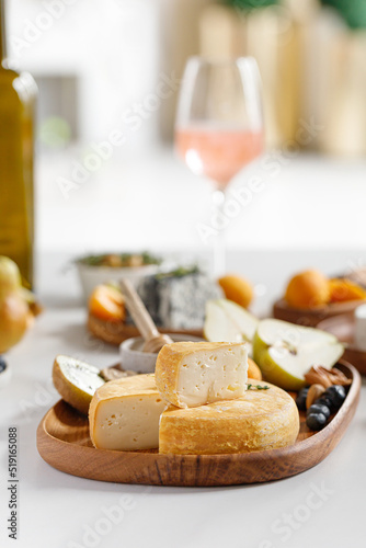Fototapeta Naklejka Na Ścianę i Meble -  French and italian cheeses. Cheese and wine concept. Reblochon, Camembert, Caciotta, Langres on wooden plates with fruits and honey. Cheese plate, dish.