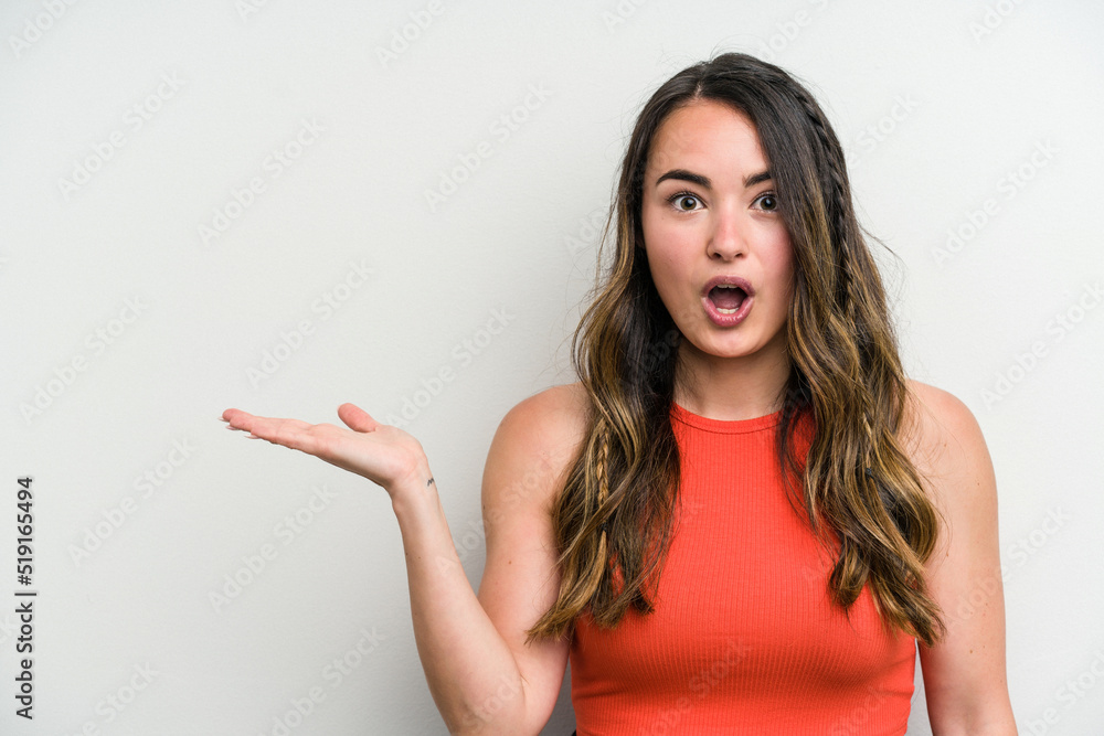 Young caucasian woman isolated on white background impressed holding copy space on palm. Young caucasian woman isolated on white background impressed holding copy space on palm.