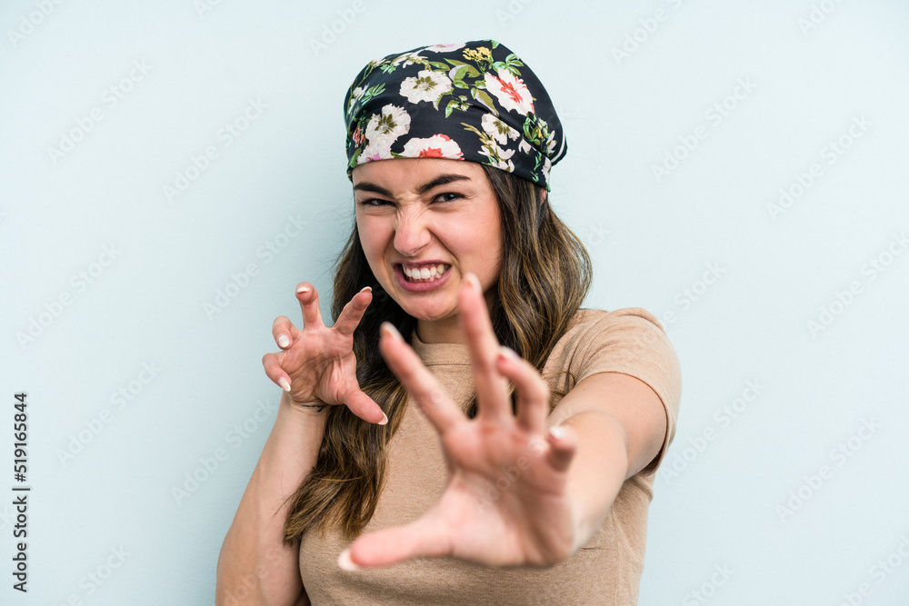 Young caucasian woman isolated on blue background showing claws imitating a cat, aggressive gesture. Young caucasian woman isolated on blue background showing claws imitating a cat, aggressive gesture.