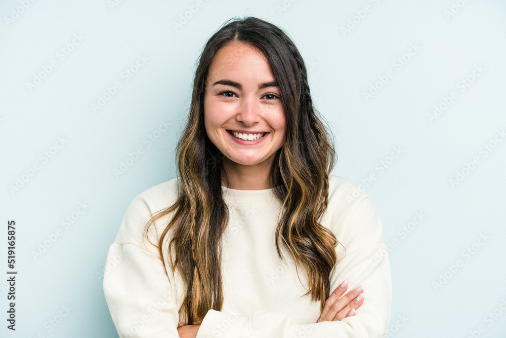 Young caucasian woman isolated on blue background who feels confident, crossing arms with determination. Young caucasian woman isolated on blue background who feels confident, crossing arms with determination.
