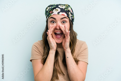 Young caucasian woman isolated on blue background saying a gossip, pointing to side reporting something.