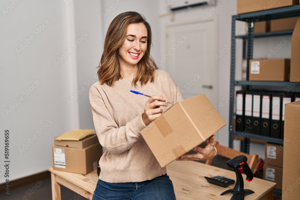 Young woman ecommerce business worker writing on package at office Young woman ecommerce business worker writing on package at office