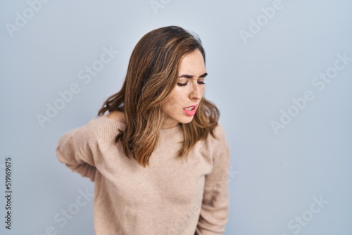 Young woman standing over isolated background suffering of backache, touching back with hand, muscular pain