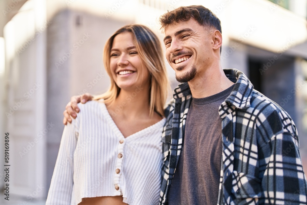Naklejka premium Young man and woman couple hugging each other standing at street