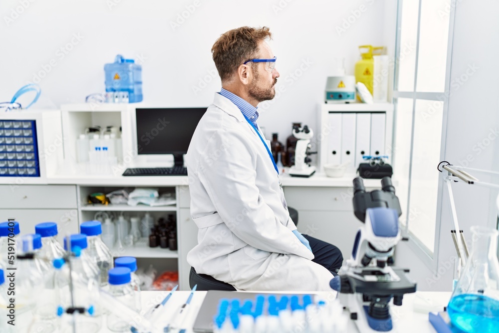 Middle age man working at scientist laboratory looking to side, relax profile pose with natural face with confident smile. Middle age man working at scientist laboratory looking to side, relax profile pose with natural face with confident smile.