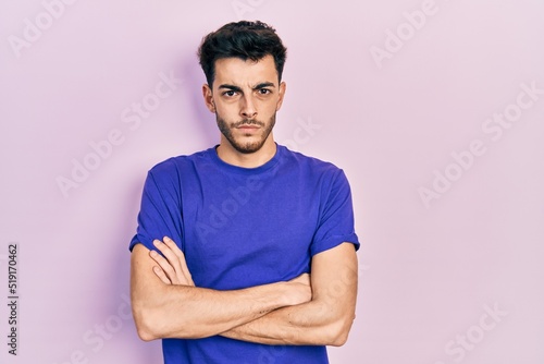 Young hispanic man wearing casual t shirt skeptic and nervous, disapproving expression on face with crossed arms. negative person.
