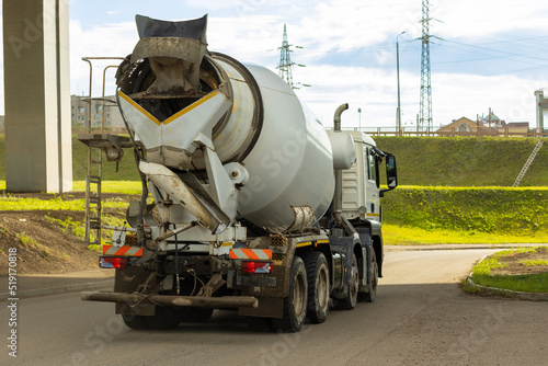 Grey mixer truck on city road is transporting cement to building site