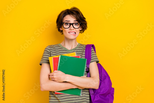 Photo of scary unsure girl dressed green t-shirt eyewear rucksack holding book scary exam isolated yellow color background