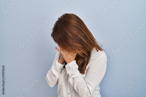 Hispanic woman standing over isolated background with sad expression covering face with hands while crying. depression concept.