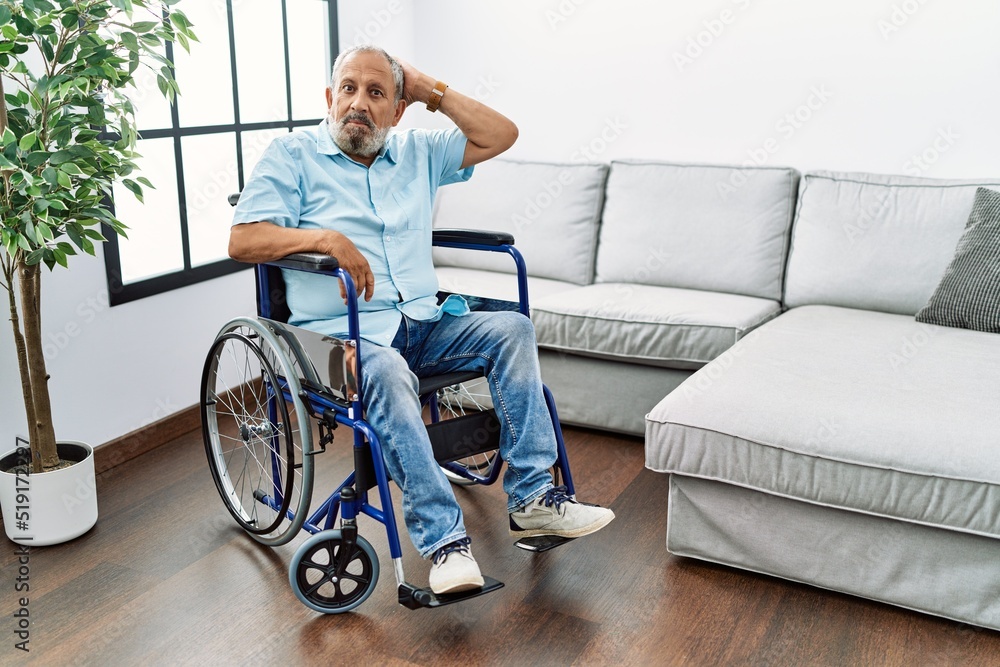Handsome senior man sitting on wheelchair at the living room confuse and wonder about question. uncertain with doubt, thinking with hand on head. pensive concept. Handsome senior man sitting on wheelchair at the living room confuse and wonder about question. uncertain with doubt, thinking with hand on head. pensive concept.