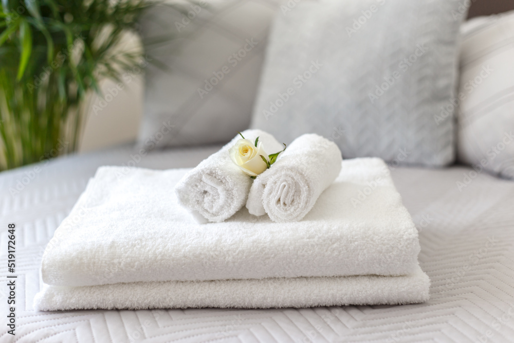 Rolled white towels on the bed in the hotel room, close up with copy space Rolled white towels on the bed in the hotel room, close up with copy space