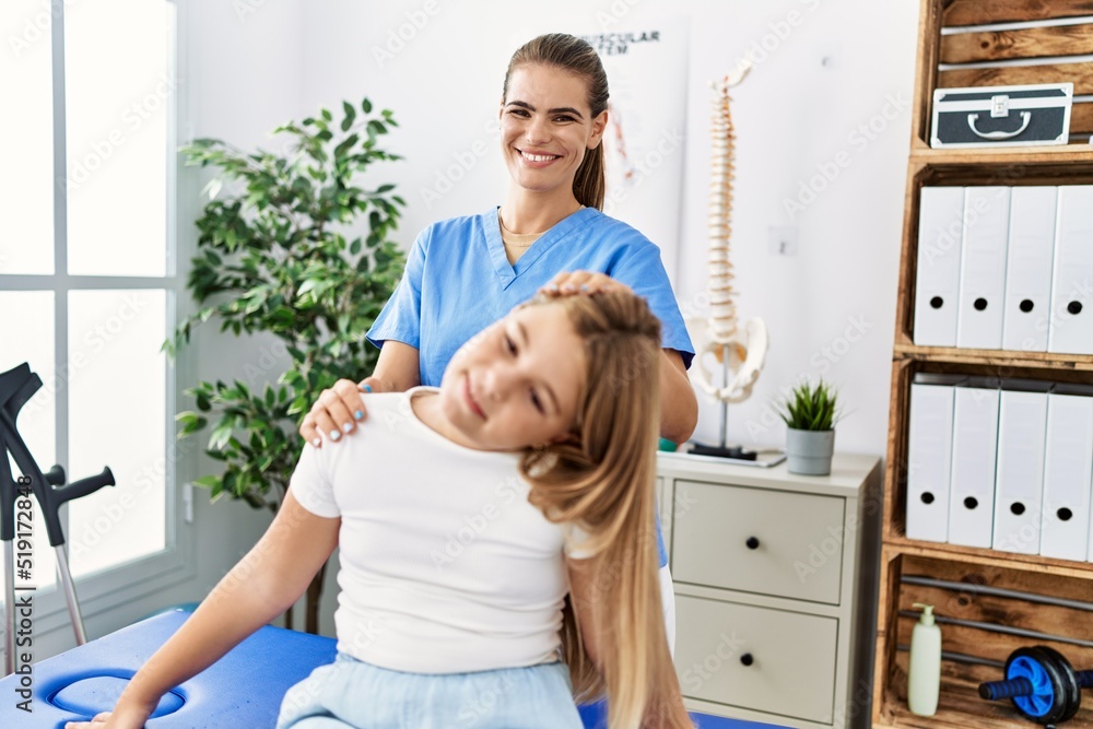 Obraz premium Woman and girl physiotherapist and patient having rehab session stretching neck at physiotherapy clinic