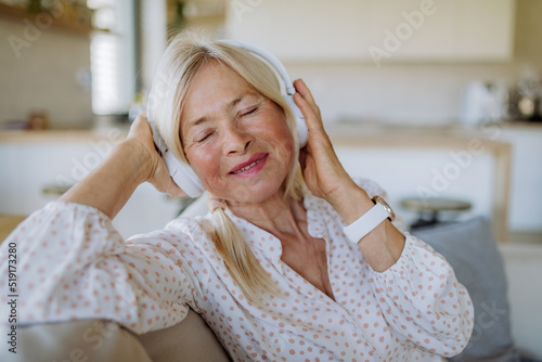 Senior woman with headphones listening to relaxation music at home