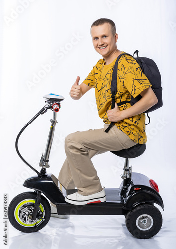 guy in an electric car. a man in the studio on a tricycle with a backpack. travel white background. electric scooter. ecological transport