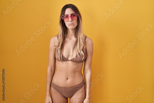 Young hispanic woman wearing bikini over yellow background depressed and worry for distress, crying angry and afraid. sad expression.