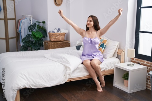 Young woman stretching arms waking up at bedroom