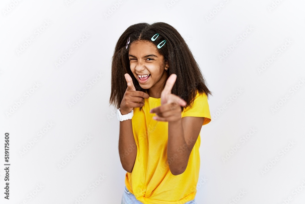 Young african american girl standing over white isolated background pointing fingers to camera with happy and funny face. good energy and vibes. Young african american girl standing over white isolated background pointing fingers to camera with happy and funny face. good energy and vibes.
