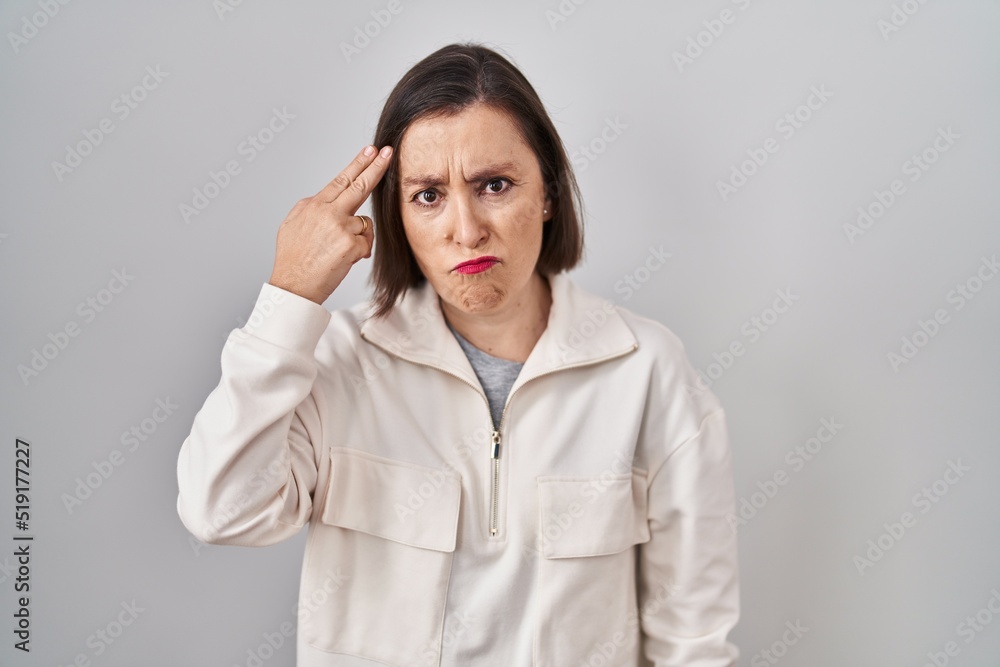 Middle age hispanic woman standing over isolated background shooting and killing oneself pointing hand and fingers to head like gun, suicide gesture. Middle age hispanic woman standing over isolated background shooting and killing oneself pointing hand and fingers to head like gun, suicide gesture.