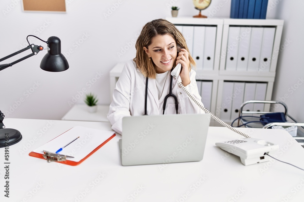 Young hispanic woman wearing doctor stethoscope talking on the telephone at clinic Young hispanic woman wearing doctor stethoscope talking on the telephone at clinic