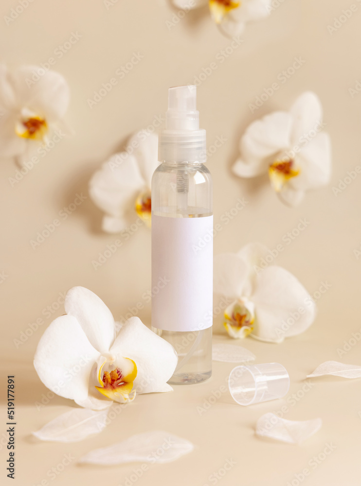 One pump dispenser bottle near white orchid flowers on light yellow close up. Mockup One pump dispenser bottle near white orchid flowers on light yellow close up. Mockup