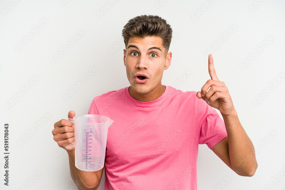 Young caucasian man holding measuring jug isolated on white background having an idea, inspiration concept. Young caucasian man holding measuring jug isolated on white background having an idea, inspiration concept.