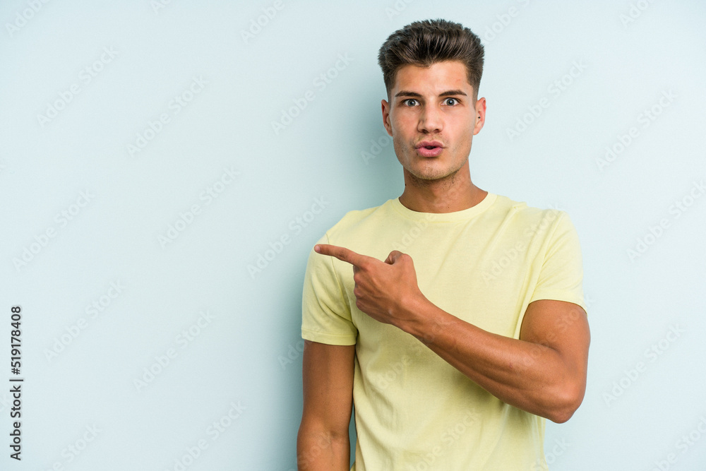 Young caucasian man isolated on blue background pointing to the side Young caucasian man isolated on blue background pointing to the side