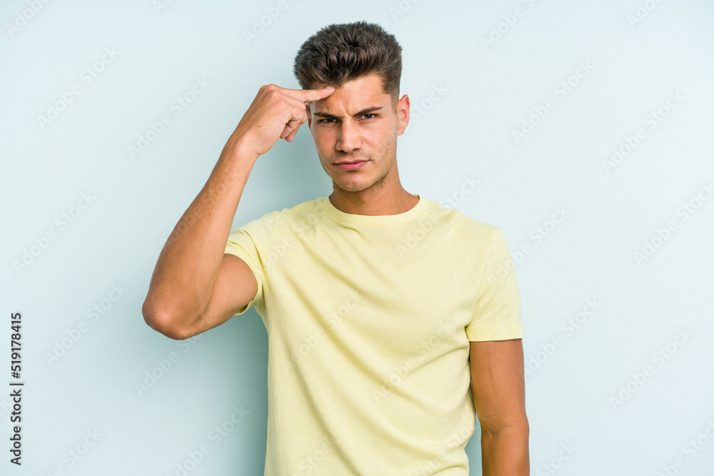 Obraz premium Young caucasian man isolated on blue background pointing temple with finger, thinking, focused on a task.