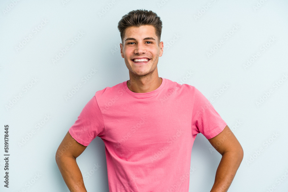 Young caucasian man isolated on blue background confident keeping hands on hips. Young caucasian man isolated on blue background confident keeping hands on hips.