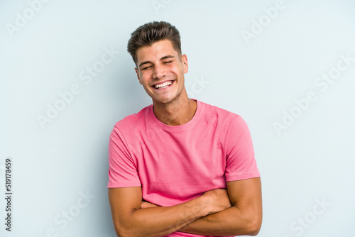 Young caucasian man isolated on blue background laughing and having fun.