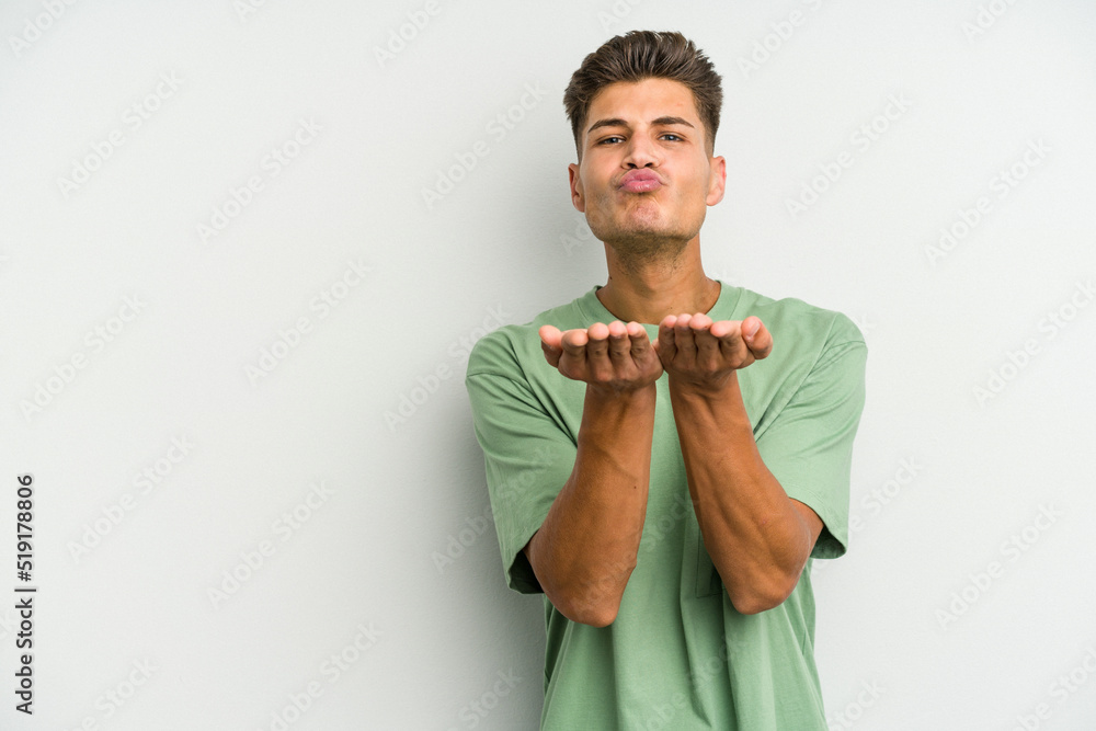 Young caucasian man isolated on white background folding lips and holding palms to send air kiss. Young caucasian man isolated on white background folding lips and holding palms to send air kiss.