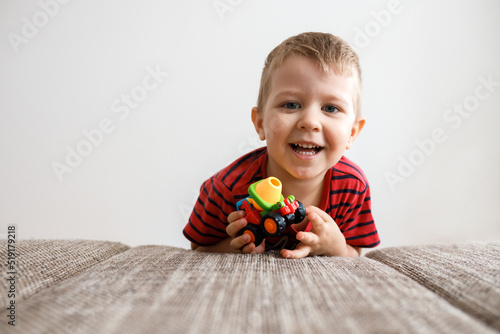 cute little boy of three with a toy in his hands at home by the couch.