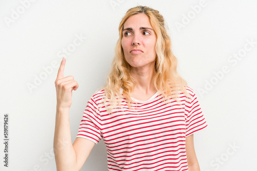 Young caucasian woman isolated on white background pointing with finger at you as if inviting come closer.
