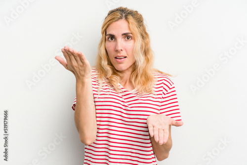 Young caucasian woman isolated on white background makes scale with arms, feels happy and confident.
