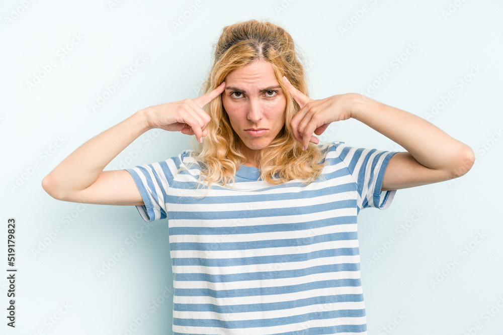 Young caucasian woman isolated on blue background focused on a task, keeping forefingers pointing head. Young caucasian woman isolated on blue background focused on a task, keeping forefingers pointing head.