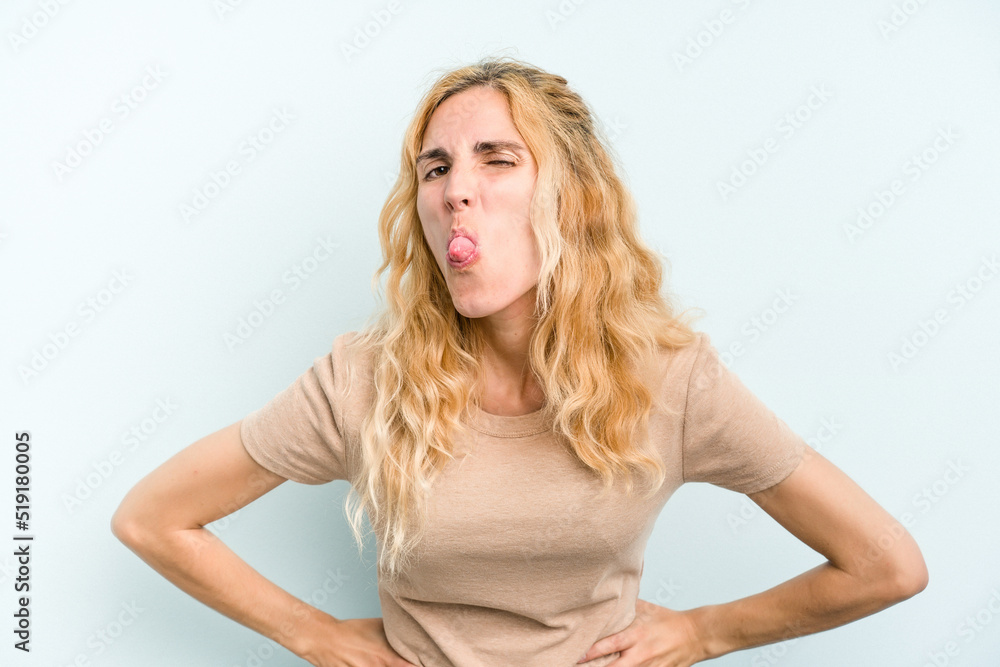 Young caucasian woman isolated on blue background funny and friendly sticking out tongue. Young caucasian woman isolated on blue background funny and friendly sticking out tongue.