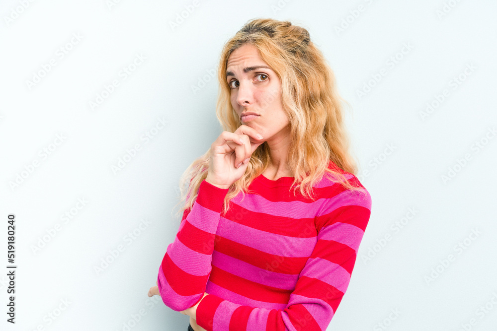 Young caucasian woman isolated on blue background thinking and looking up, being reflective, contemplating, having a fantasy. Young caucasian woman isolated on blue background thinking and looking up, being reflective, contemplating, having a fantasy.