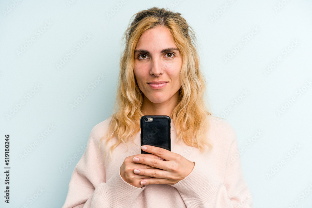 Young caucasian woman holding mobile phone isolated on blue background Young caucasian woman holding mobile phone isolated on blue background