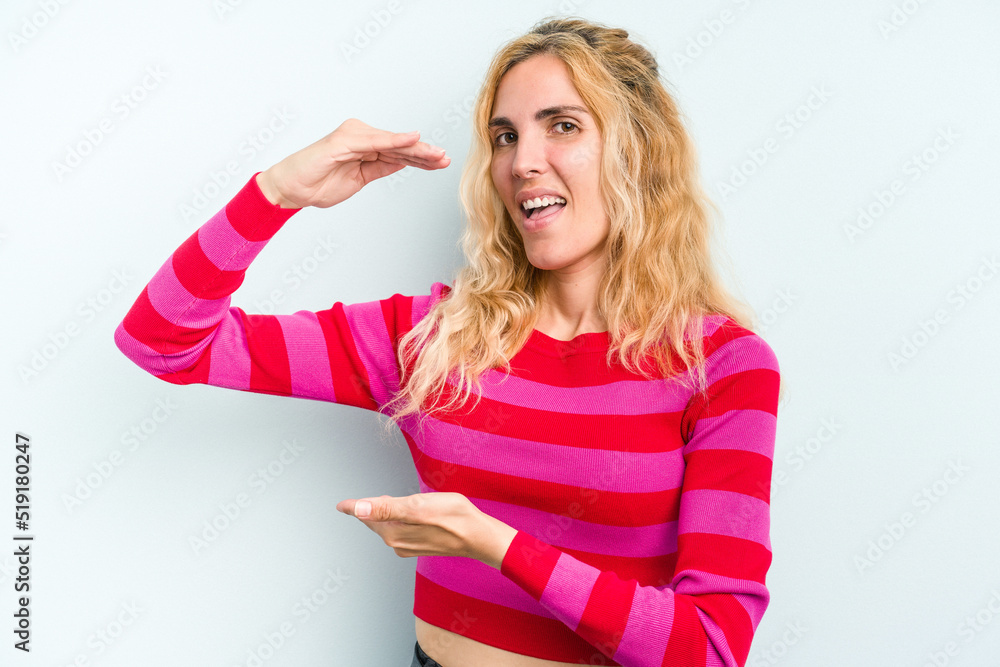 Young caucasian woman isolated on blue background holding something little with forefingers, smiling and confident. Young caucasian woman isolated on blue background holding something little with forefingers, smiling and confident.