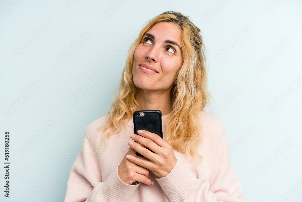 Young caucasian woman holding mobile phone isolated on blue background Young caucasian woman holding mobile phone isolated on blue background
