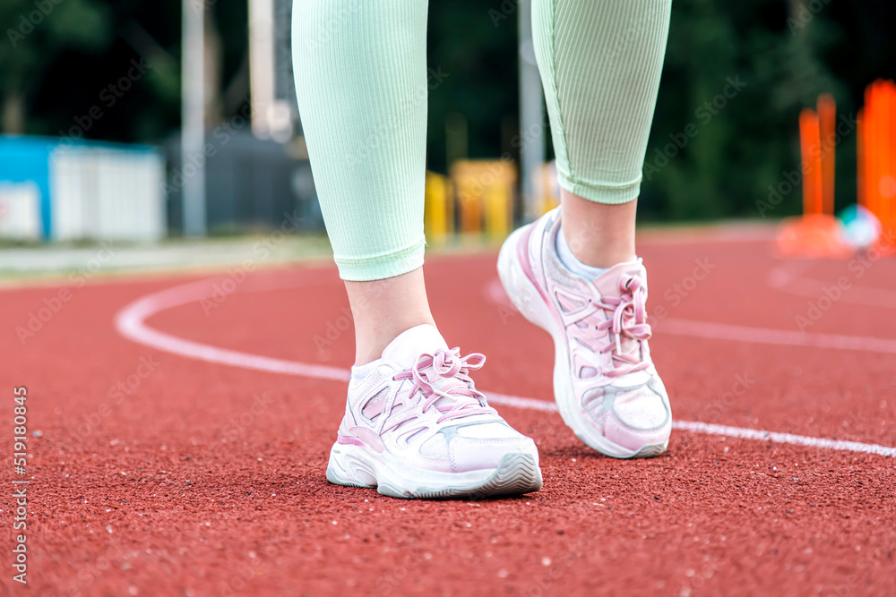 Close-up, female legs in sneakers at the stadium. Close-up, female legs in sneakers at the stadium.