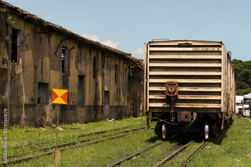 Old and rusty train car stopped beside a dilapidated port warehouse. Old and rusty train car stopped beside a dilapidated port warehouse.