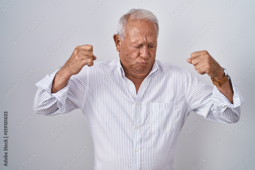 Senior man with grey hair standing over isolated background showing arms muscles smiling proud. fitness concept. Senior man with grey hair standing over isolated background showing arms muscles smiling proud. fitness concept.