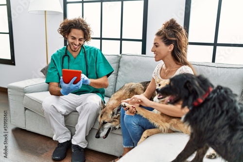 Man and woman wearing veterinarian uniform using touchpad at home