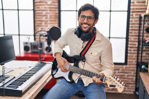 Young hispanic man musician playing electrical guitar at music studio