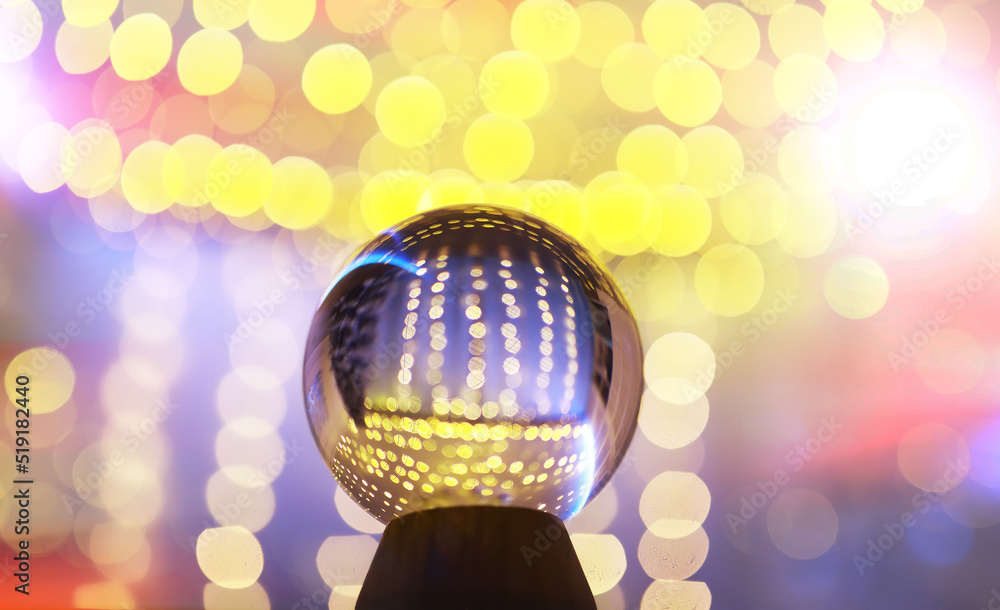 Fototapeta premium Crystal Ball on the floor with bokeh, lights behind. Glass ball with colorful bokeh light, celebration concept.