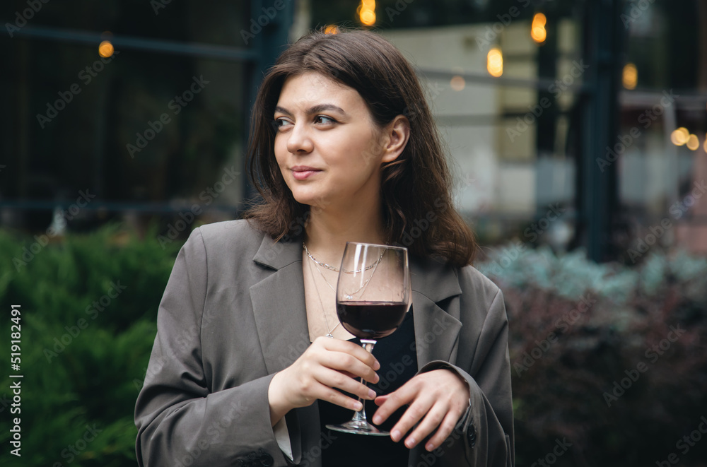 A young woman with a glass of wine outside near a restaurant. A young woman with a glass of wine outside near a restaurant.